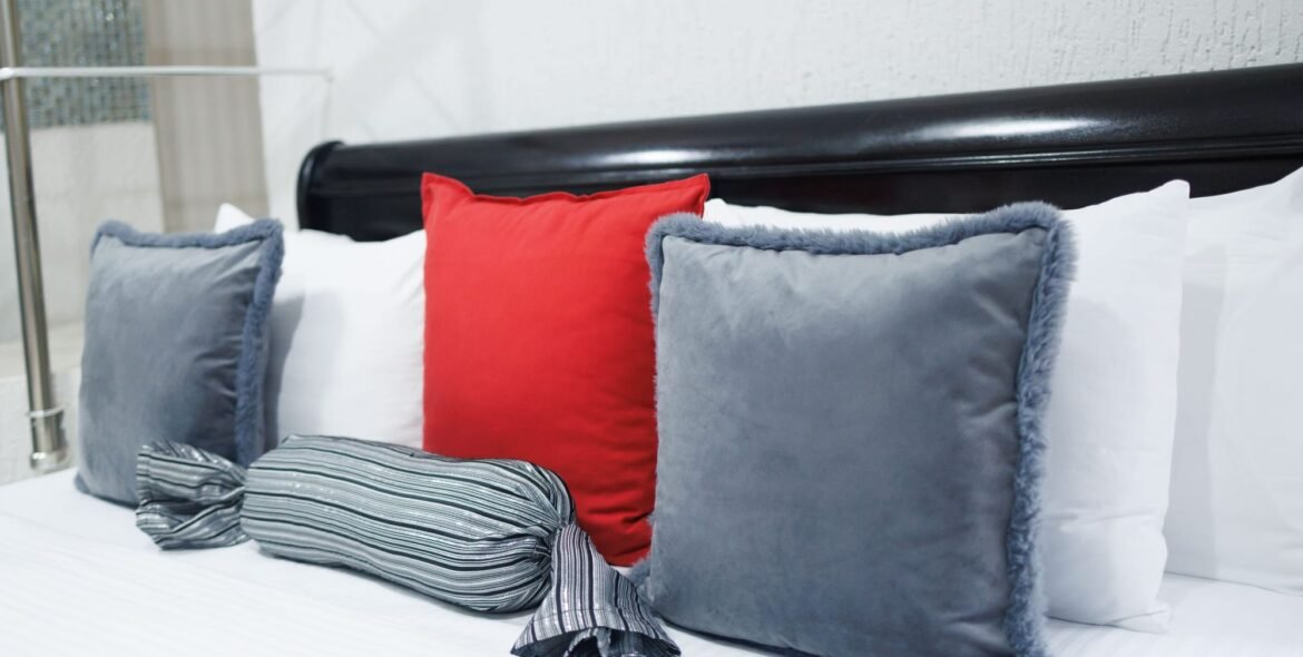 Blue-grey and red cushions on a queen bed