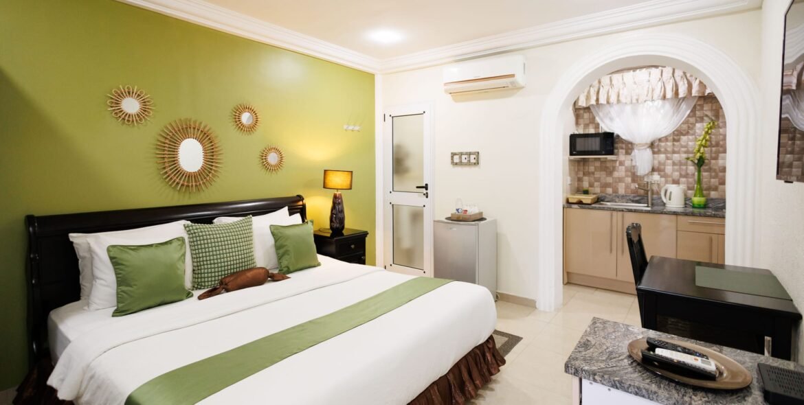 Wide view of a queen room with a green accent wall