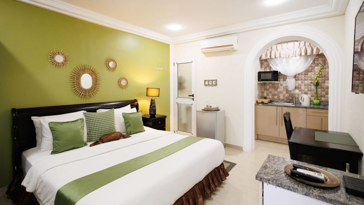 Wide view of a queen room with a green accent wall