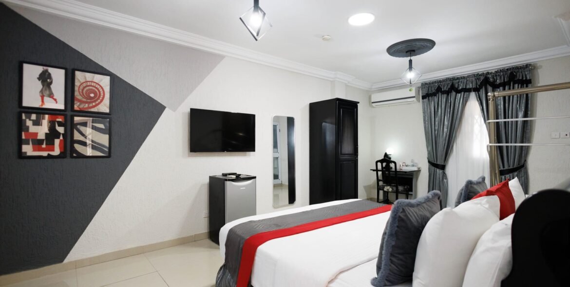 Wide view of a queen room with red and grey bedding